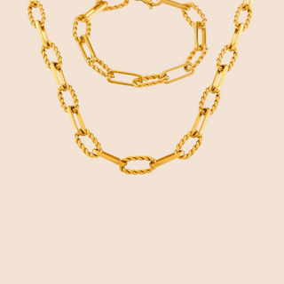 Gold chain necklace and bracelet on a white fabric background