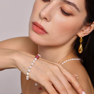 Woman wearing gold earrings and pearl jewelry on a neutral background